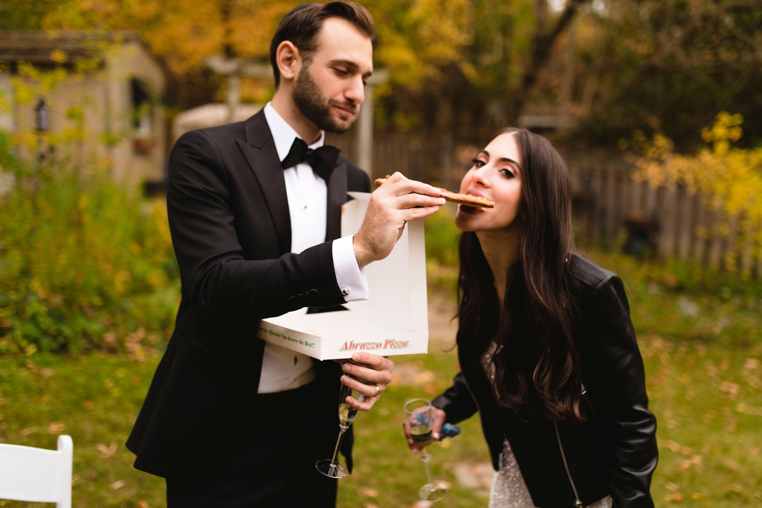 The bride and groom share a slice of pizza