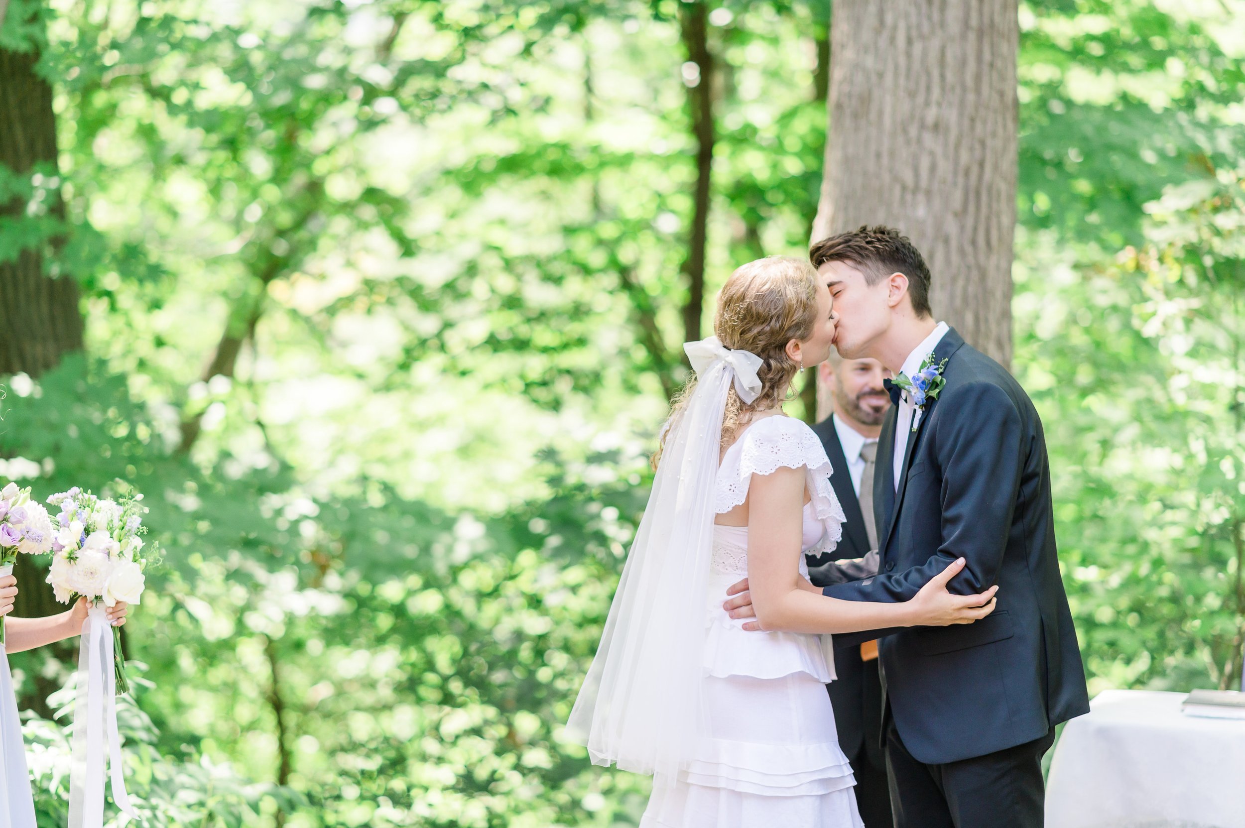 bride and groom kiss under the trees