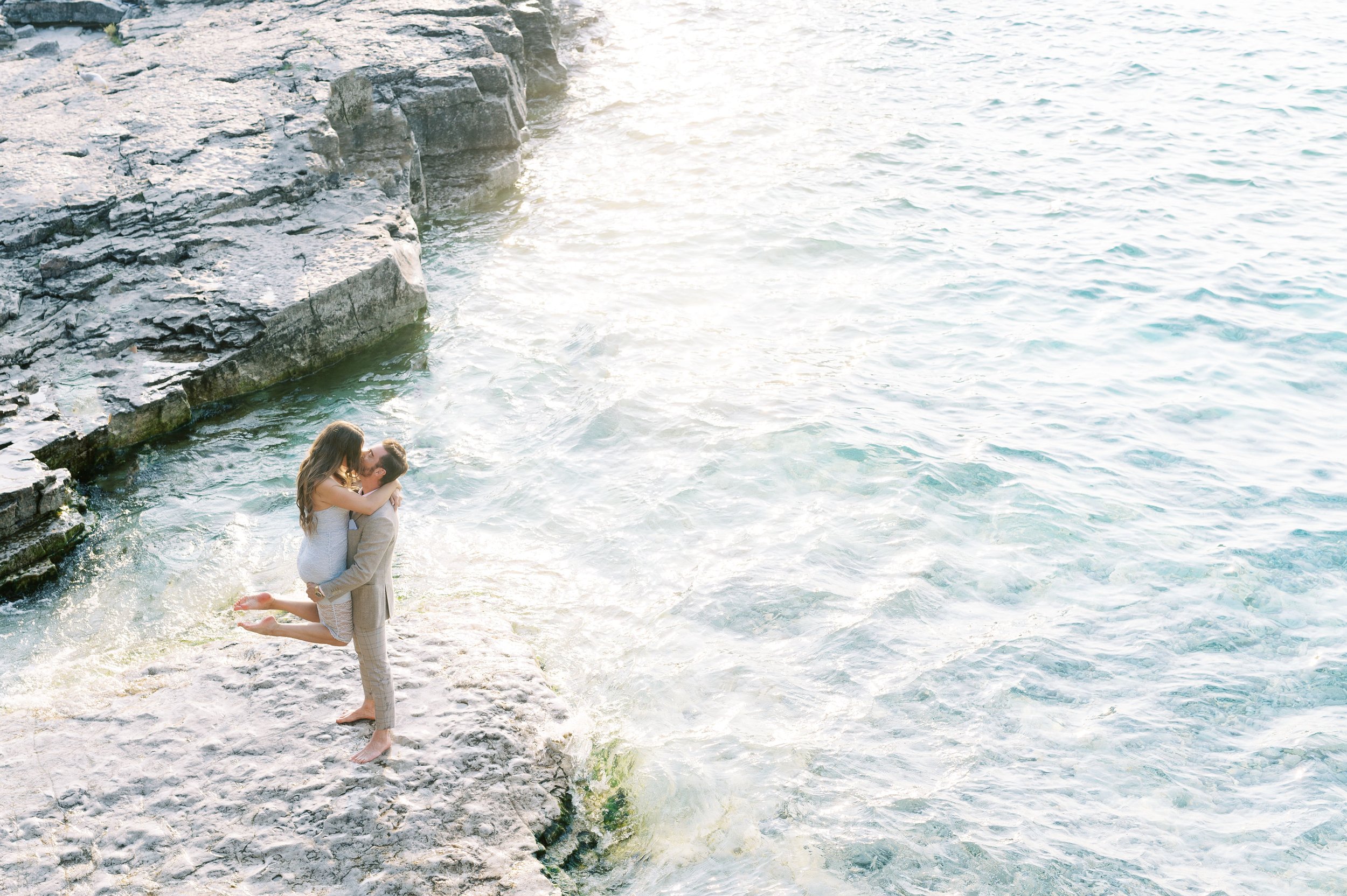 man holds his wife in his arms for a kiss in owen Sound. Engagement shoot photos of Mercedes and Russel