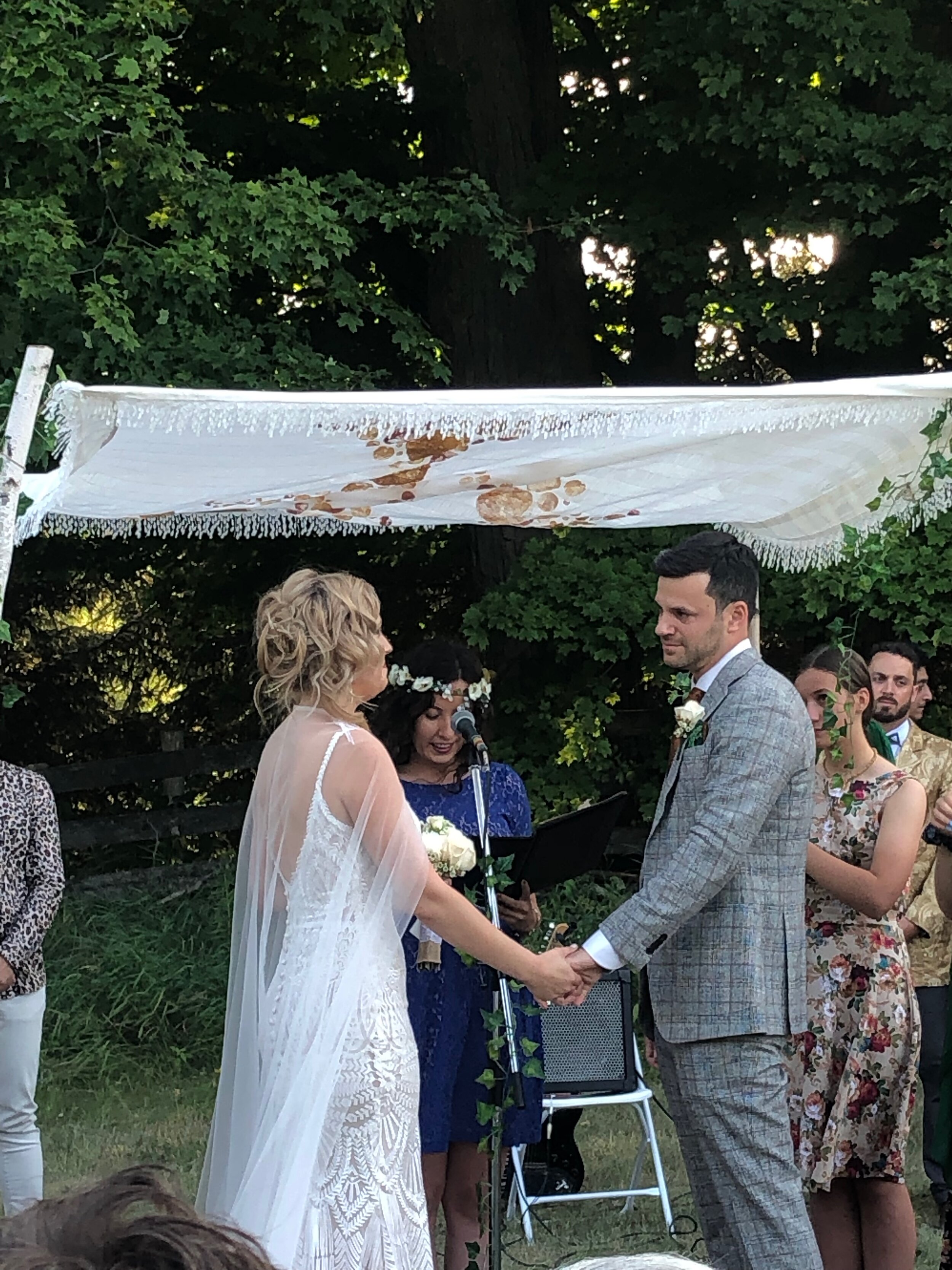 The bride and groom under the Chuppah, surrounded by friends and family.