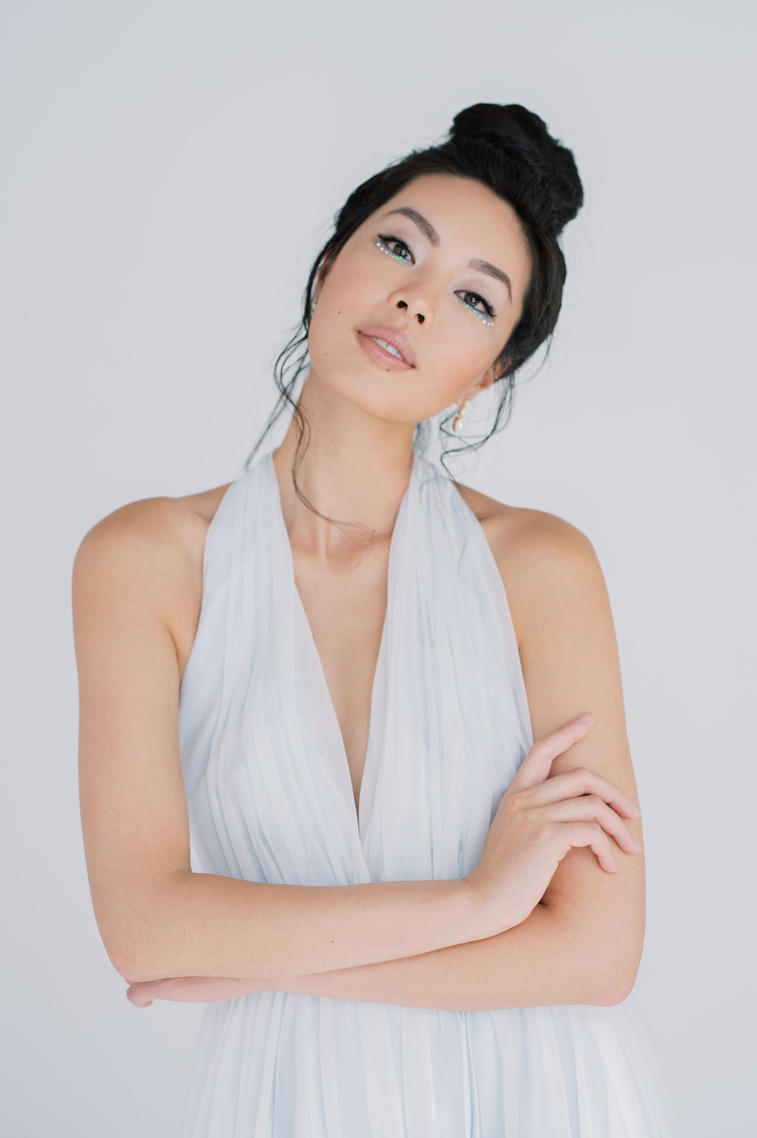 brunette model with high bun and shimmery makeup in a pale blue dres