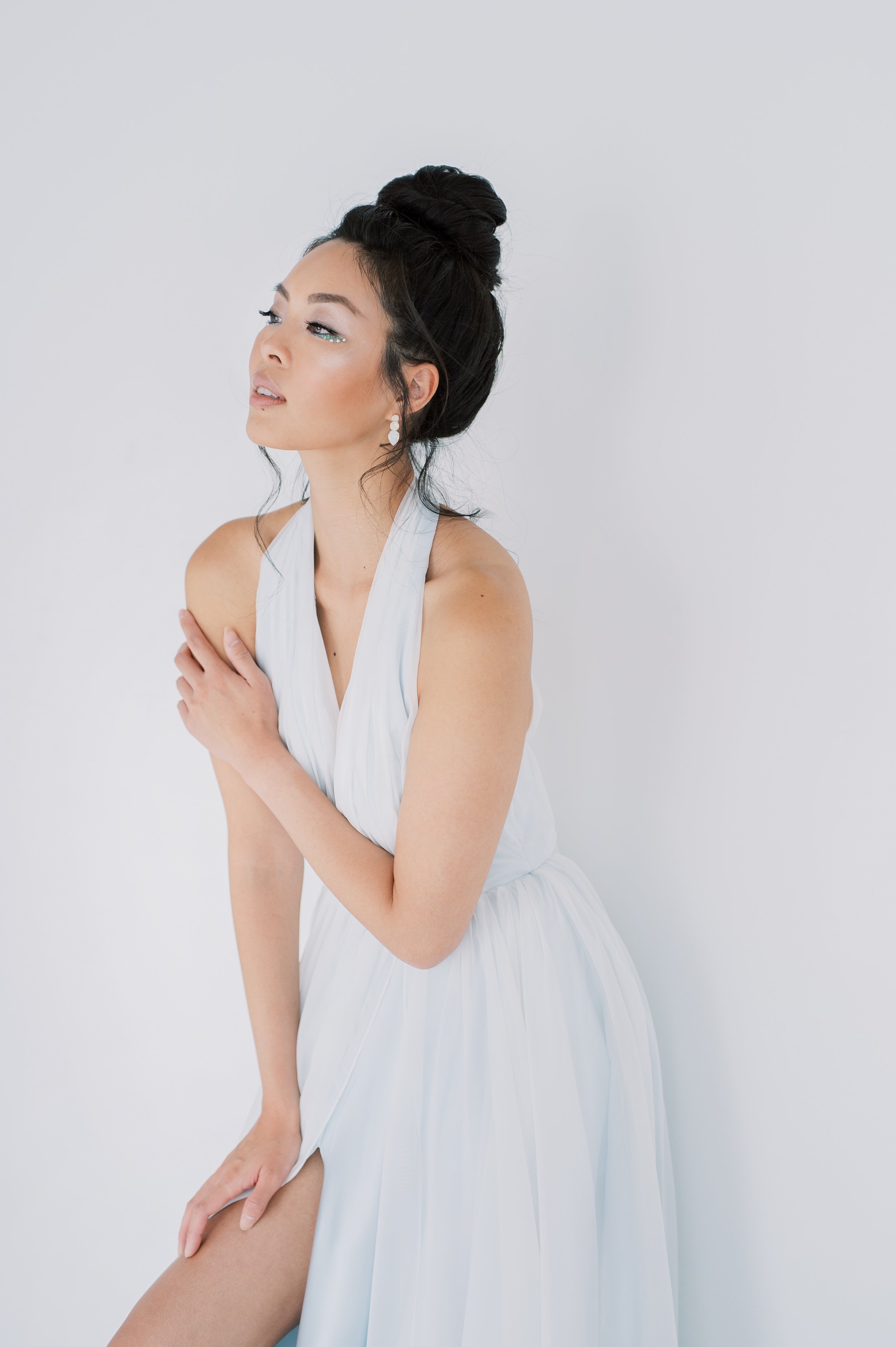 brunette model with high bun and shimmery makeup in a pale blue dres