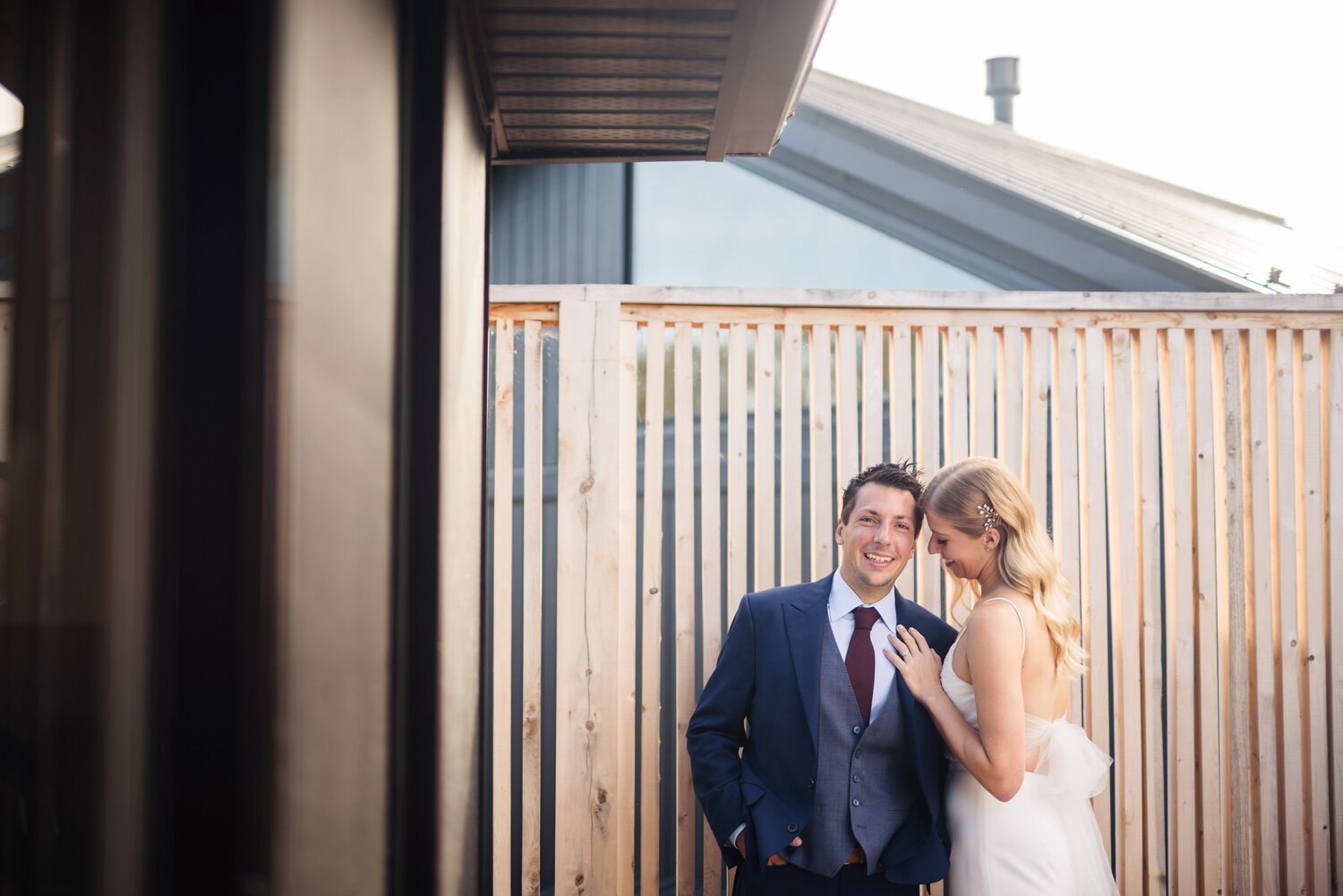 The bride affectionately feels the lapel of her hubby to be outside their cottage at Wander the Resort in Prince Edward County.