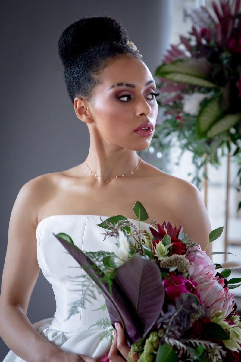 bride looks off into the distance. she has a berry coloured smokey eye and pinky gloss on.