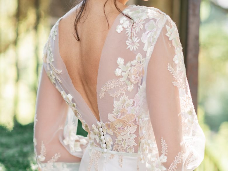 Beautiful indian looking model looks over her shoulder wearing a tiara and shimmery makeup with a dark lip with a lace appliquee dress over silk in front of Graydon Hall Manor at the gate. sun is shining bright!